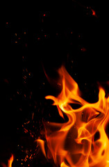 Fototapeta na wymiar Fiery flame with sparks on a black background. Texture (element) for barbecue or cooking.