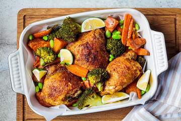Baked chicken with vegetables, gray background, top view.