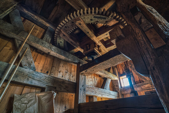 A wooden cog set in motion by the rotating blades of an historical wind mill. Industrial interior with a toothed windmill gear, part of a milling or grinding machine, conveys vintage concept - Denmark