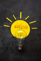 Light bulb on a dark background, around the rays of colored paper and the inscription Idea. Creativity concept.