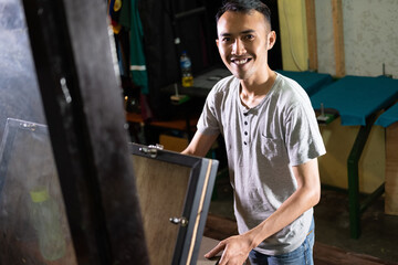 Portrait of a young confident worker working by manual silk screen