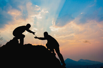 teamwork success concept. hiker help each other silhouette in mountains with sunlight.