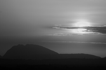 High Dynamic Range Silhouette in Monochrome of hills against beautiful  sunset and clouds in the sky