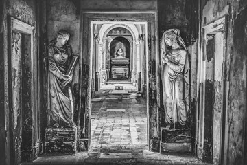 cemetery long corridor in black and white with two statues 