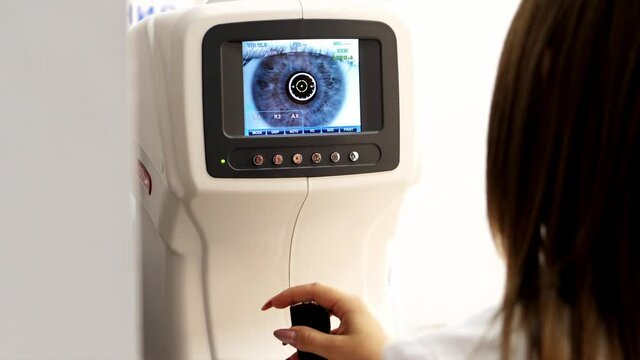 Optician doctor working with the refractometer machine. Eye exam for man at optical store.