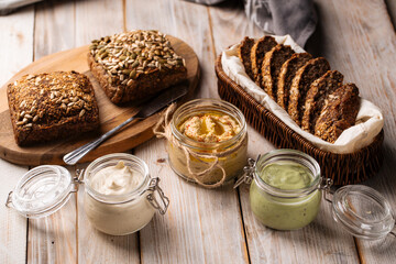 Different spreading sauces in jars with cut bread
