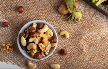 Fototapeta premium Variation of dried nuts on a autumn theme background with leafs and candle light.