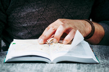 Main d'un homme en train de lire un guide touristique