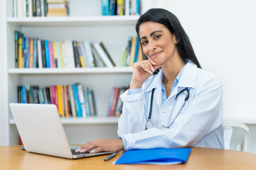 Latin american female doctor working at computer