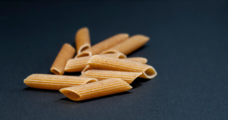 Penne rigate type of noodes isolated on black background. Traditional Italian cuisine, popular healthy dish for lunch or dinner.