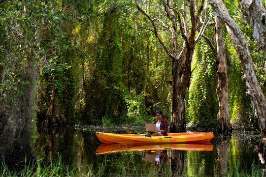 On vacation female tourist using laptop on kayak in the botanic rainforest. Smart telecommunication make life easier to contact, get information. 5G communication technology, internet networks concept