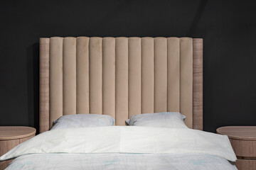 Bedroom, stylish made bed on a dark background. Getting ready to sleep.