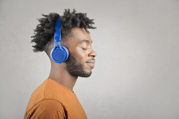 Afro young man with closed eyes listening to music on headphone