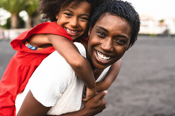 Happy African family having fun on the beach during summer holidays - Afro mother and daughter...