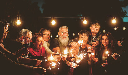 Happy family celebrating with sparklers fireworks at night party - Group of people with different...