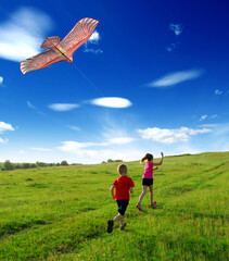  boy and girl run with kite in the field