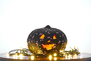 black coloured pumpkin with glitter on wooden stool in front of a white backdrop