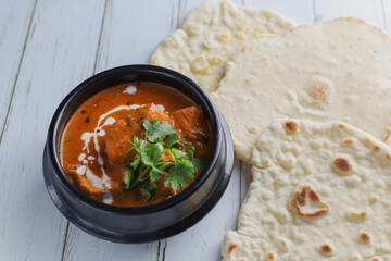 Butter chicken bowl and naan bread on wooden table. Curry - Meal, Indian food.