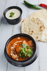 Butter chicken bowl and naan bread on wooden table. Curry - Meal, Indian food.