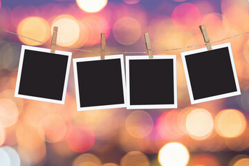 Four blank instant photo frames hanging on a rope, on holiday lights bokeh background - Powered by Adobe