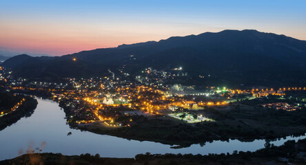 Aerial view of the ancient small illuminated town and view of the merger of two rivers at night © Luka