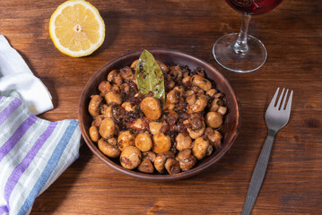 Vegan mushroom fricassee with garlic in a clay plate on a rustic wood background top view - mushrooms with garlic