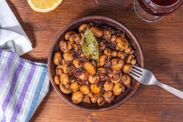 Vegan mushroom fricassee with garlic in a clay plate on a rustic wood background top view - mushrooms with garlic