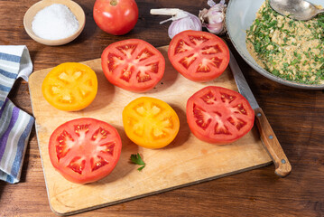 Tomatoes Provencal - cut in half the tomatoes and ingredients for cooking food on a wooden table, top view.