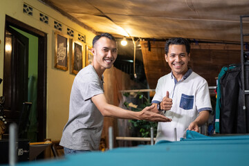 Obraz premium Asian men smile when meeting customers at the workshop, customers with thumbs up are satisfied with a good screen printing