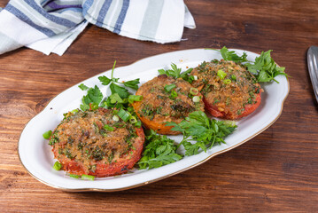 Provencal tomatoes - baked tomato halves with breadcrumbs and herbs on an oval dish, rustic background