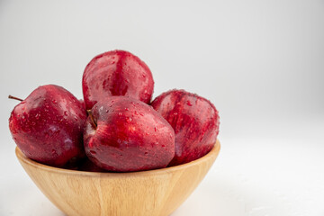Pile of red apple in wooden bowl with clear water drop on 
shell surface texture pattern isolated, white background