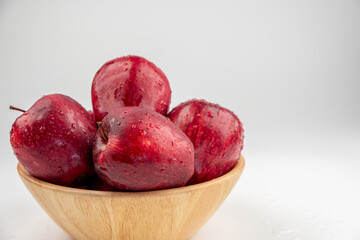 Pile of red apple in wooden bowl with clear water drop on 
shell surface texture pattern isolated, white background