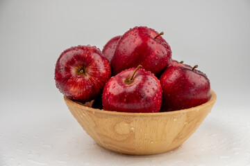 Pile of red apple in wooden bowl with clear water drop on 
shell surface texture pattern isolated,...