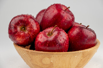 Pile of red apple in wooden bowl with clear water drop on 
shell surface texture pattern isolated, white background