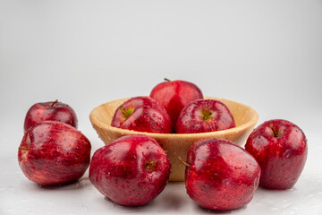 Pile of red apple in wooden bowl with clear water drop on 
shell surface texture pattern isolated, white background