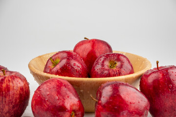 Pile of red apple in wooden bowl with clear water drop on 
shell surface texture pattern isolated, white background