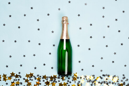 Champagne bottle with black and gold stars and circle confetti on the blue background. Christmas, New Year or birthday or wedding festive concept. Top view and flat lay.