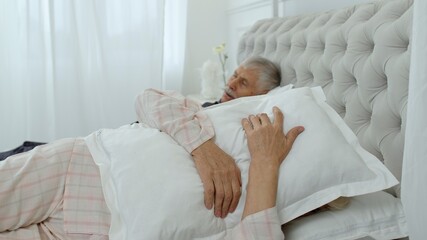 Obraz na płótnie Canvas Senior grandparents couple lying and sleeping in bed. Woman getting disturbed with man snoring