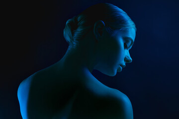 Night. Portrait of female fashion model in neon light on dark studio background. Beautiful...