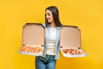 Girl on a yellow background holds two pizzas. Copy space