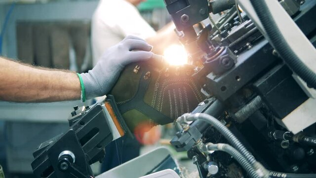 Factory worker shaping shoe with a machine. Lens flare