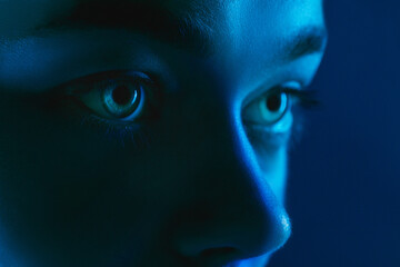 Look. Portrait of female fashion model in neon light on dark studio background. Beautiful caucasian...