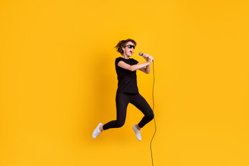 Fototapeta na wymiar Full length body size view of skinny funky cheerful girl jumping singing concert rock sound isolated bright yellow color background