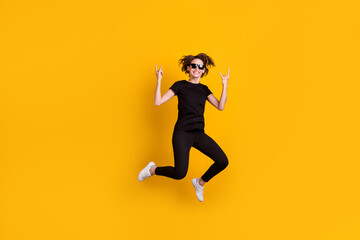 Plakat Full length body size view of attractive cool naughty playful cheery girl jumping showing horn symbol isolated bright yellow color background