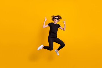 Fototapeta na wymiar Full length body size view of skinny cool crazy cheerful girl jumping showing double horn sign isolated shine yellow color background