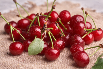 Bowl with red cherry on sackcloth background, top view