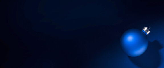 Light blue round matt Christmas ball. Christmas ornament standing on blue background.