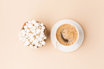 White beech mushrooms or Shimeji mushroom and cup of coffee on pastel beige paper background.