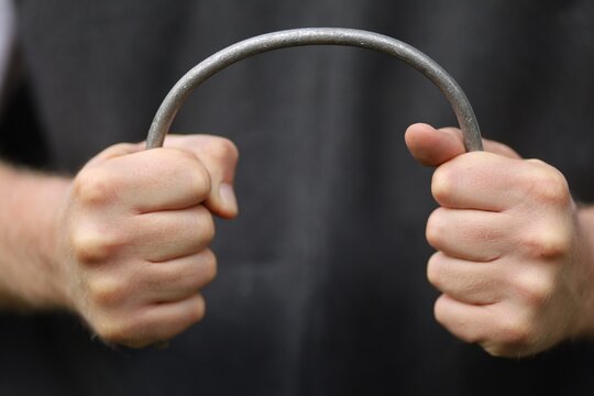 Strong hands bend a metal rod