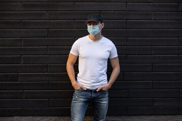 Man in white t-shirt standing against brick wall, mockup design